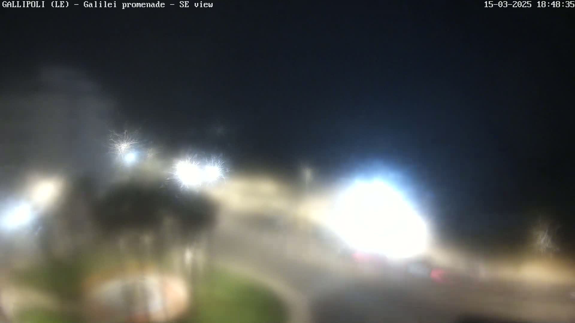 A hazy night scene shows blurry lights from vehicles and streetlights around a curved road.