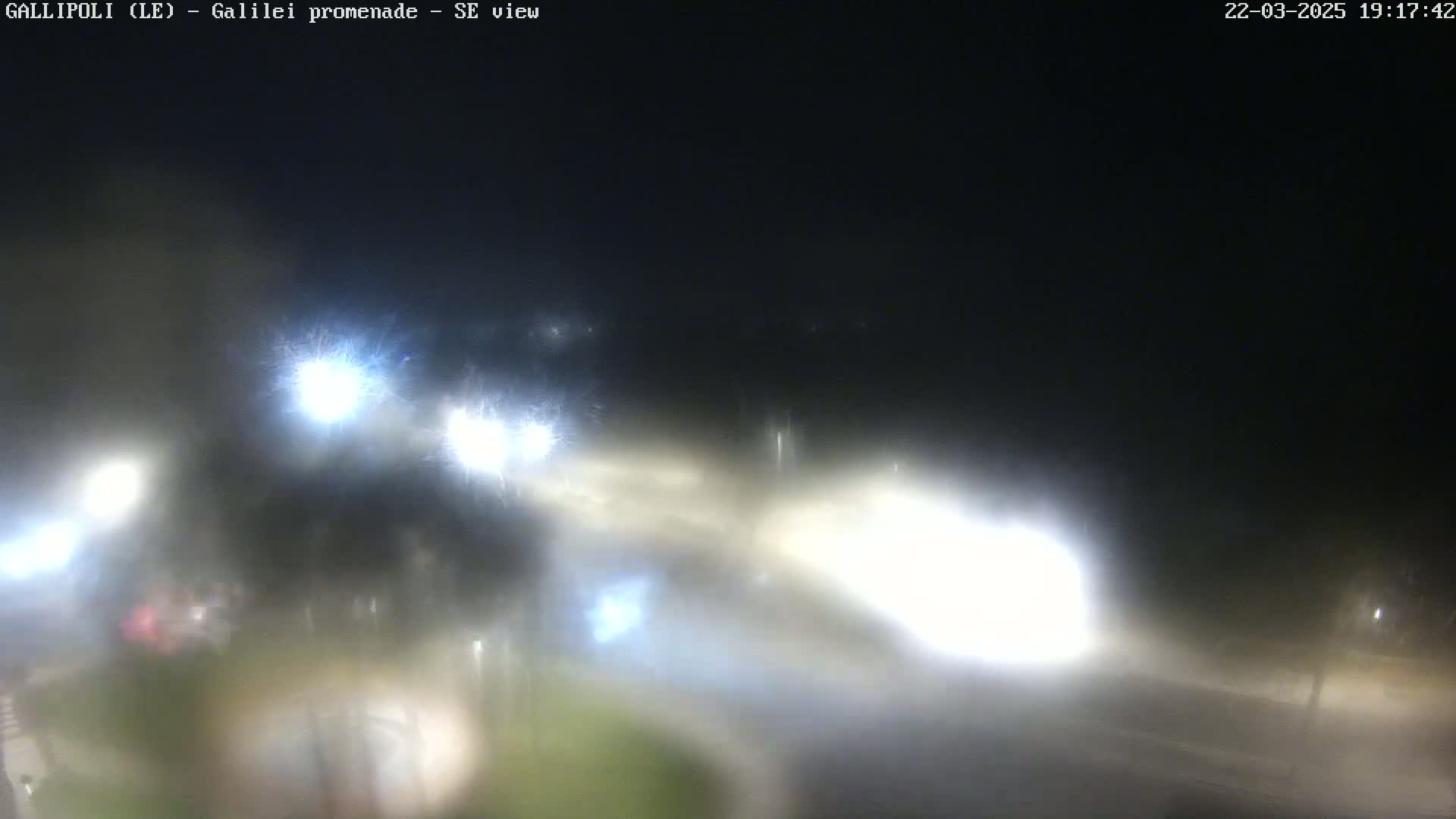 A nighttime, blurry view of a road with vehicle headlights visible through rain or fog.