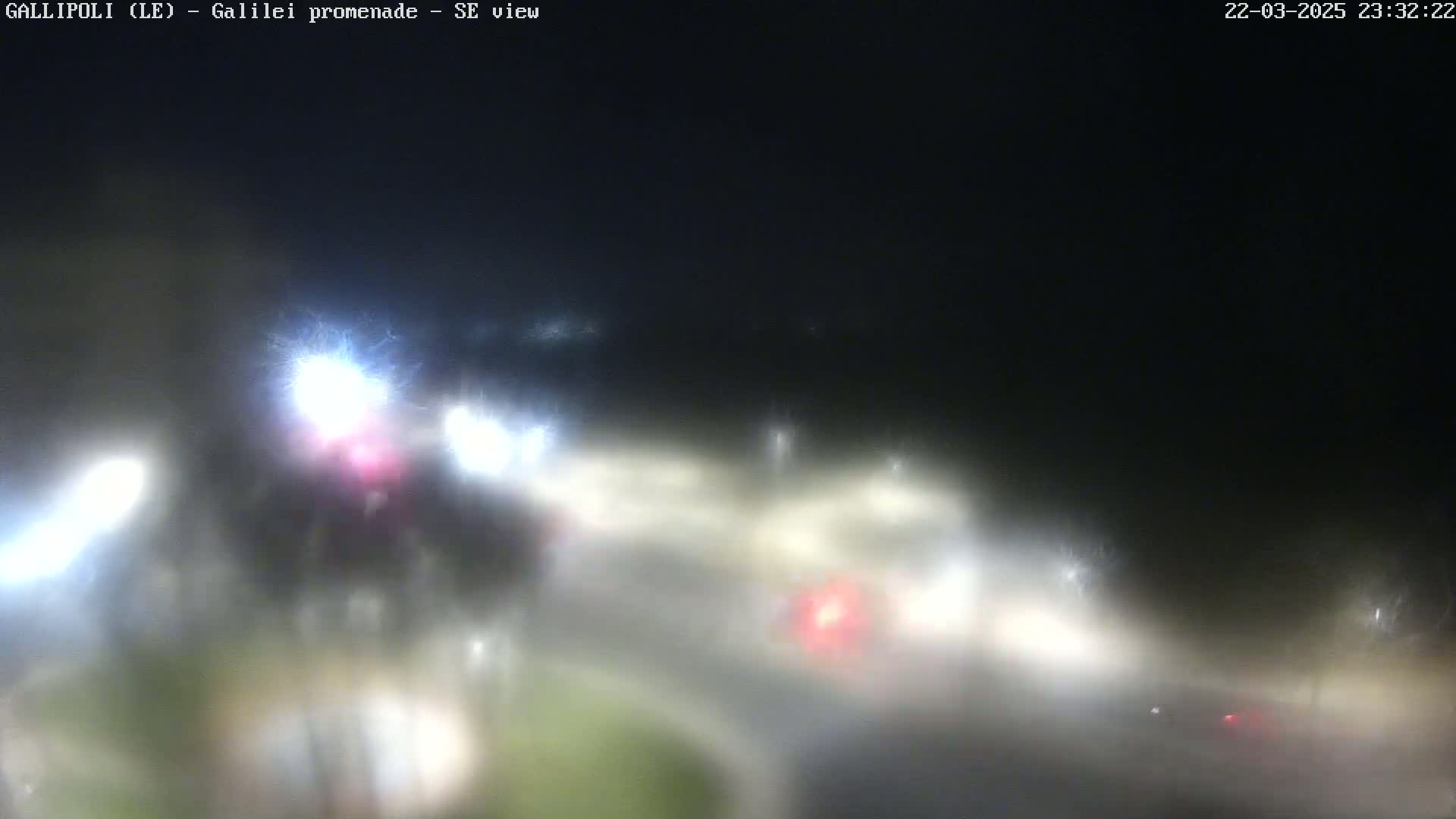 A blurry nighttime view of a foggy road with indistinct vehicles and streetlights.