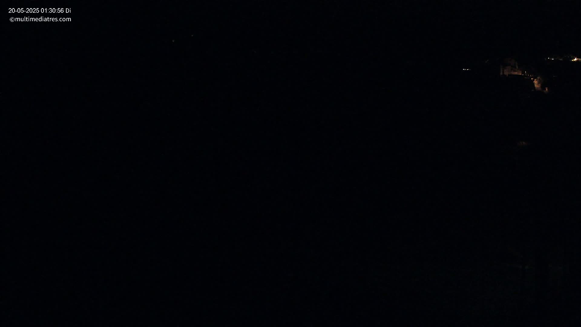 A dark, nighttime scene shows a few distant lights in the upper right corner.
