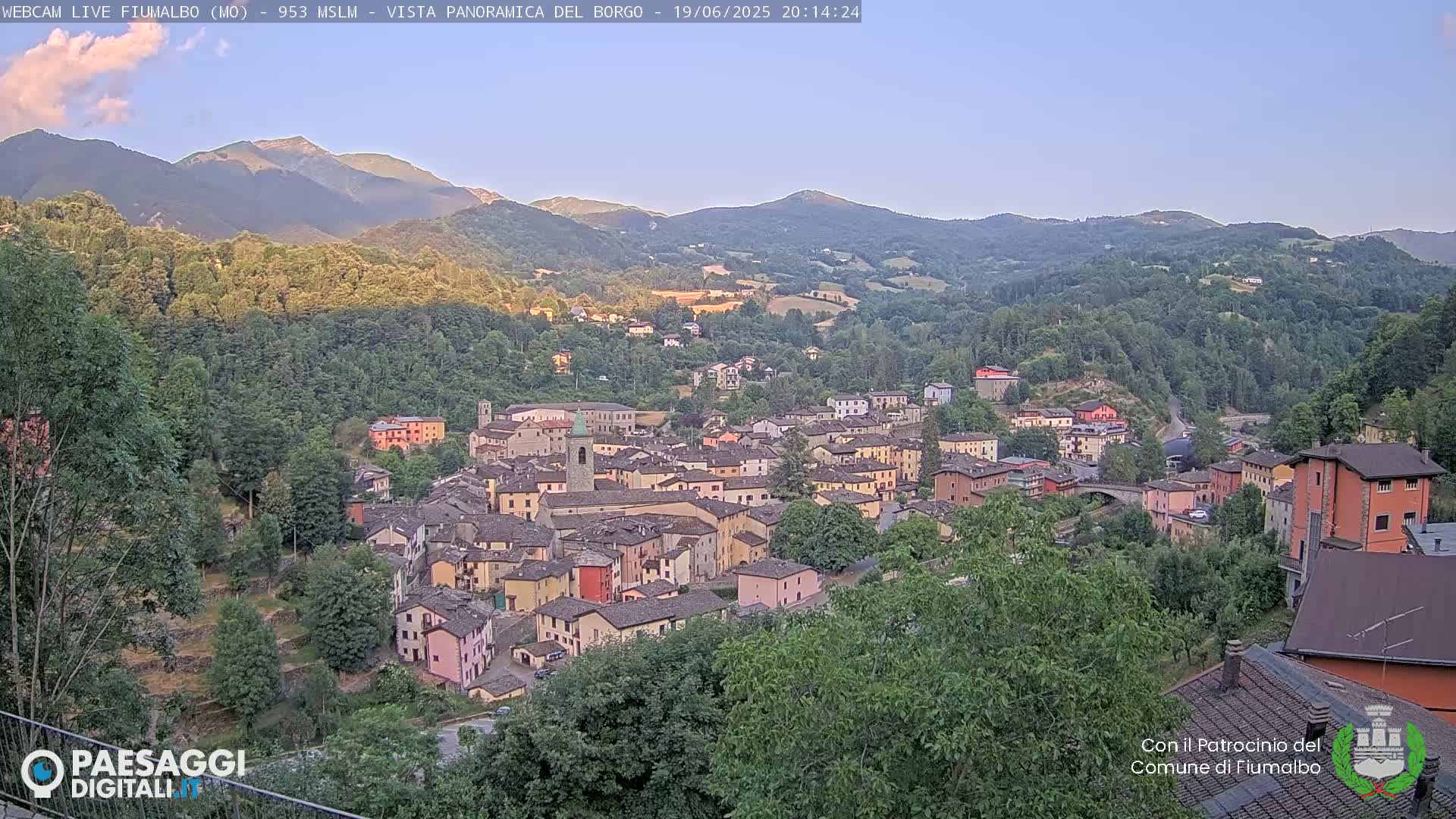 A small town nestled in a valley between mountains, under a clear evening sky.