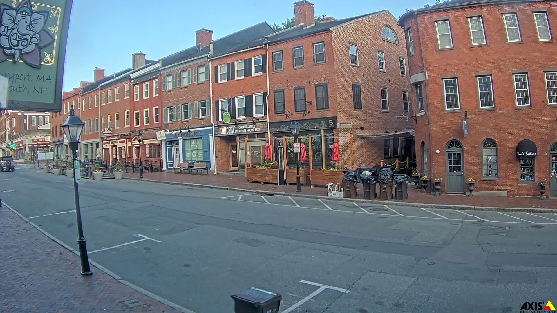 A mostly empty street lined with brick buildings under a clear, sunny sky.