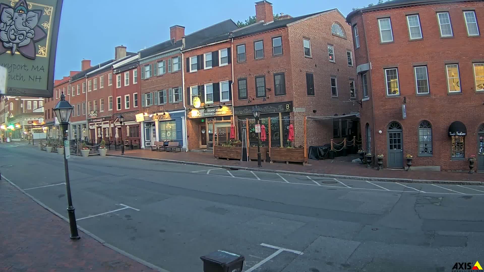 A mostly empty street lined with brick buildings under a clear, twilight sky.
