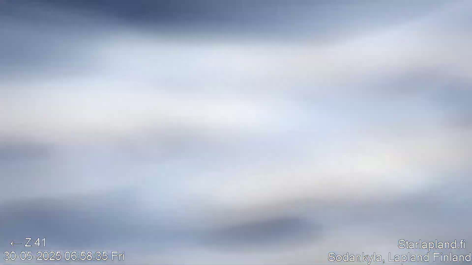 A blurry, light-blue and white image depicts an overcast sky.