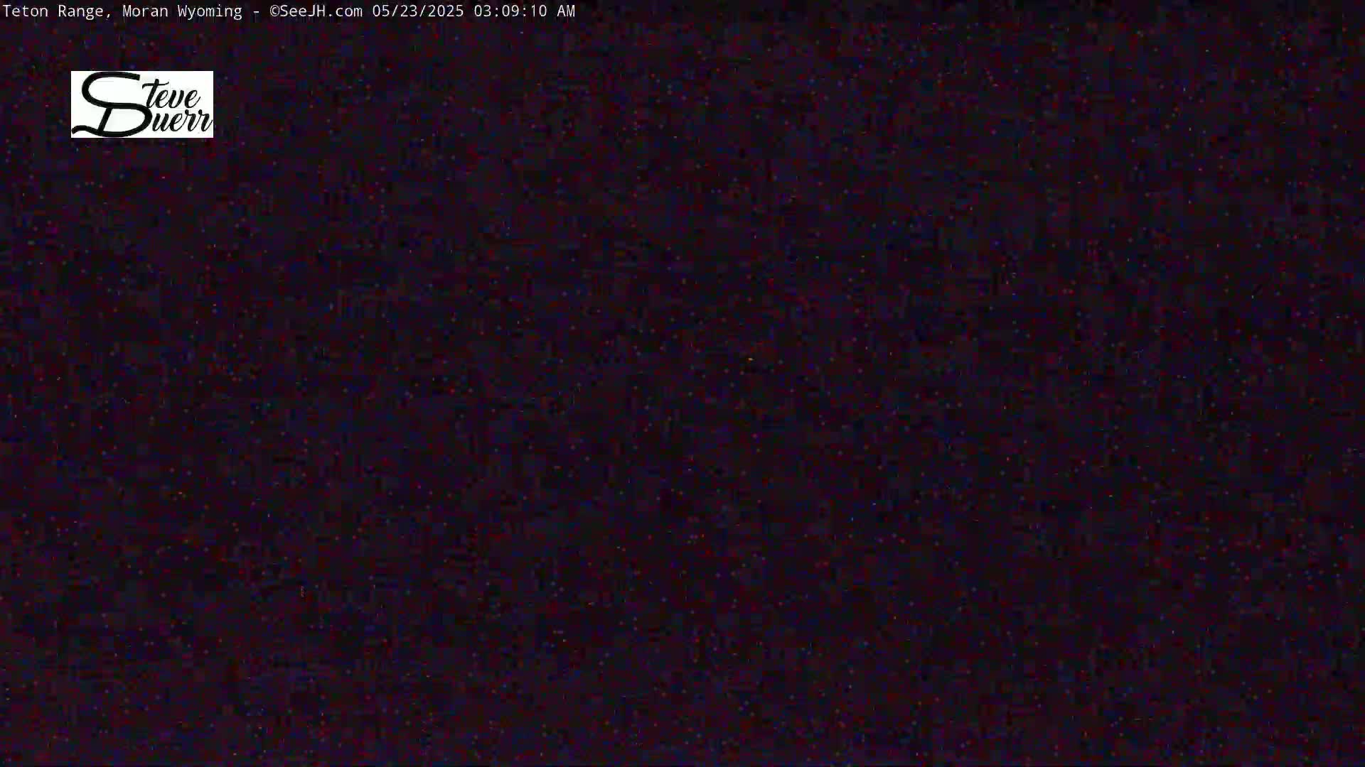 A grainy, dark image shows a mostly black scene with scattered specks of light.