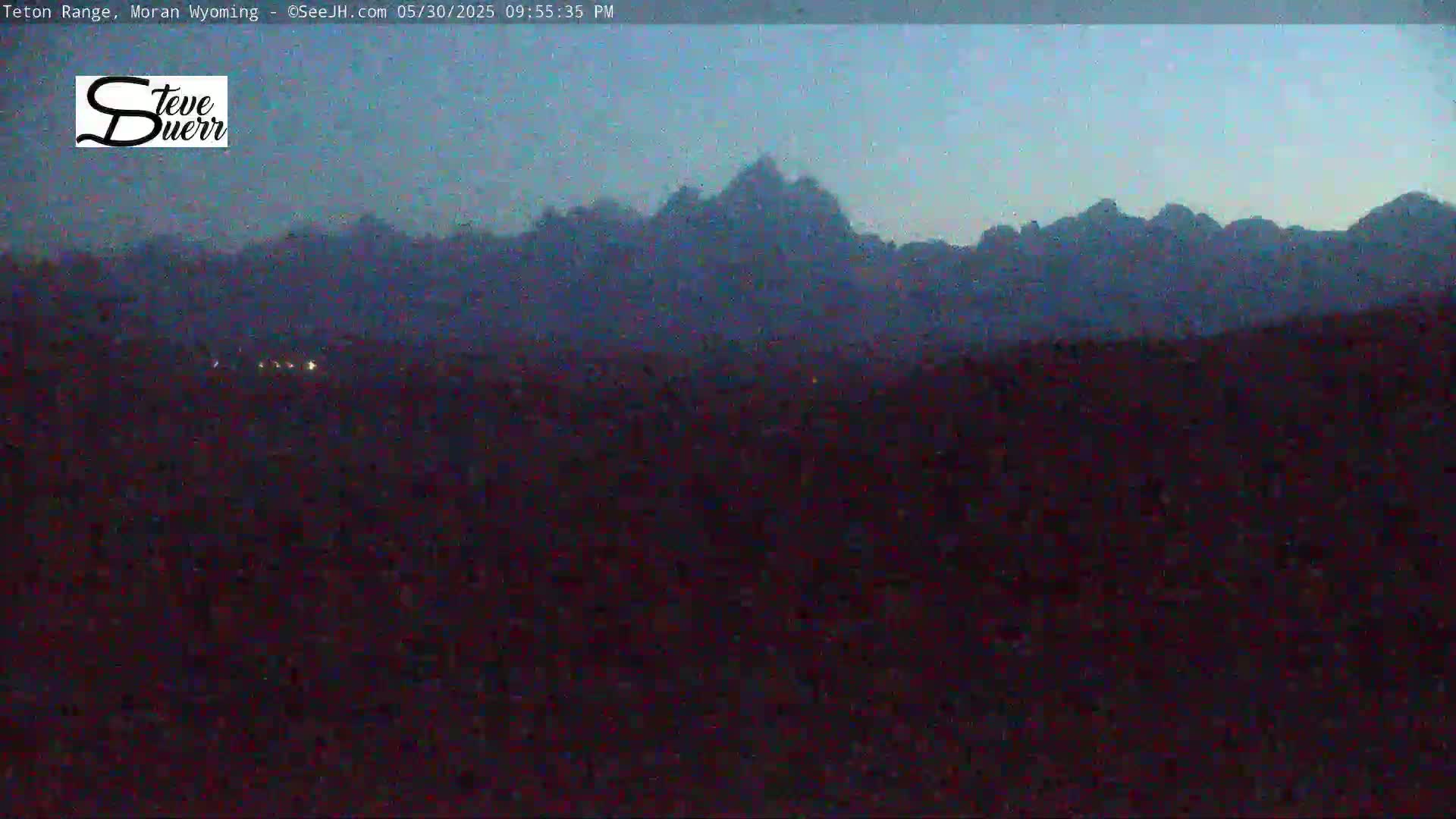 A dark, mountainous landscape is visible under a twilight sky.