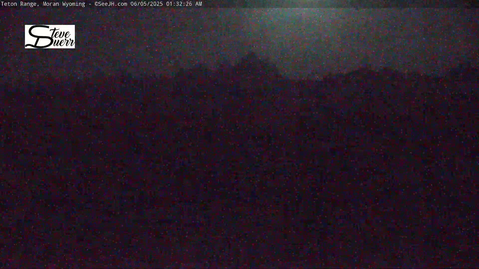 A dark, nighttime image shows a blurry, indistinct landscape under a mostly clear sky.
