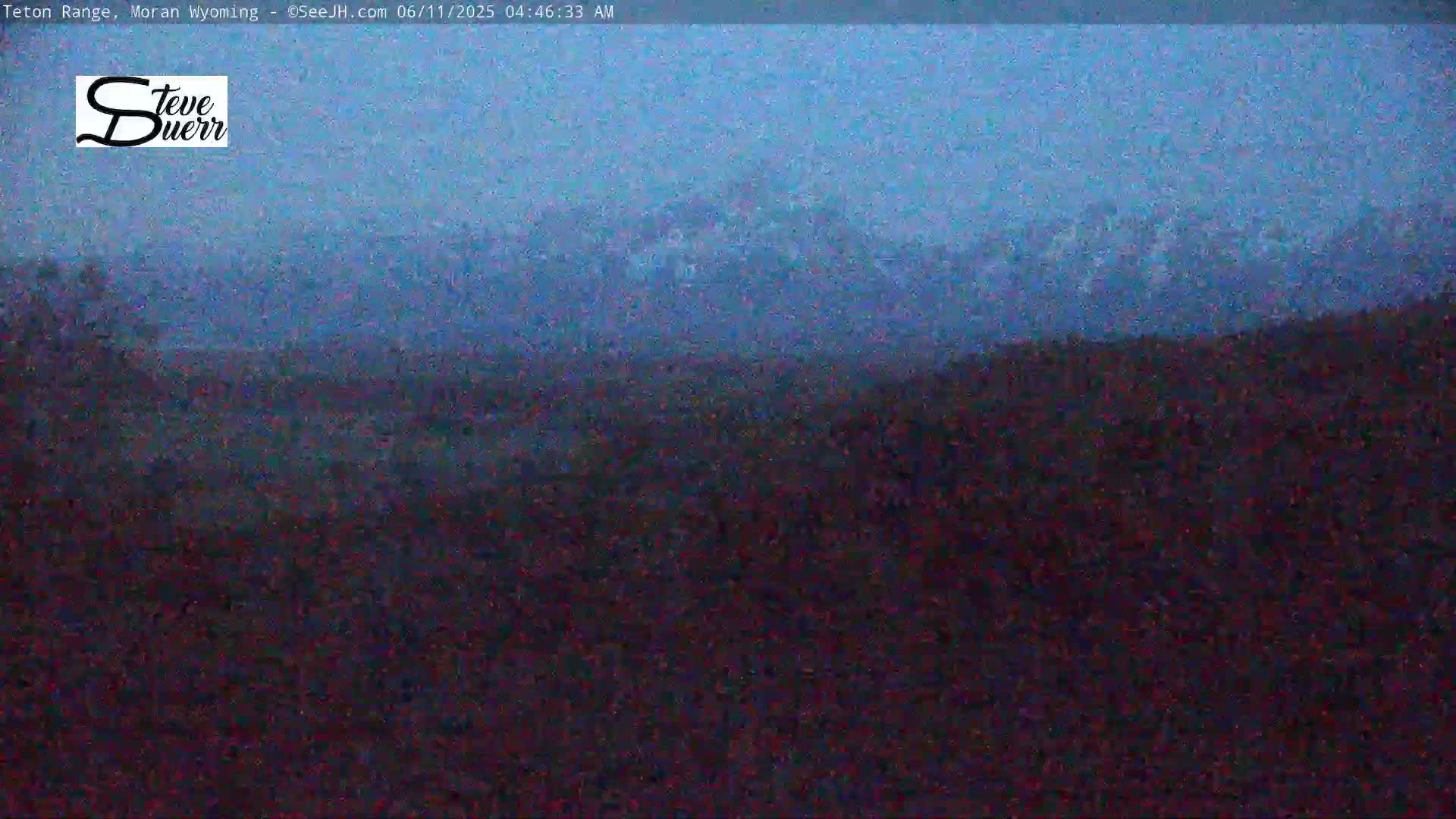 A hazy, dark blue landscape shows distant mountains under an overcast sky.