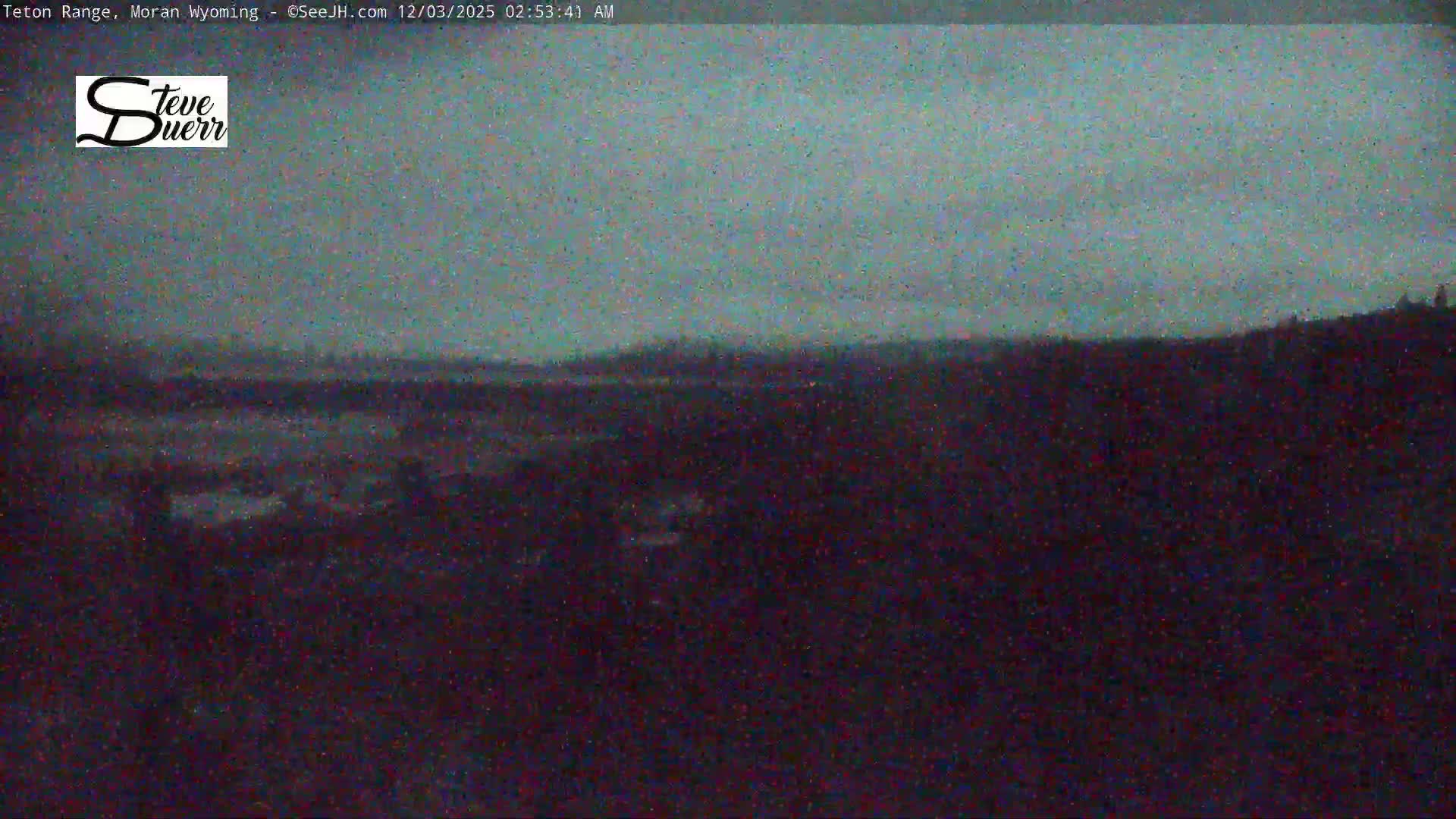 A dark and very grainy nighttime landscape is visible, showing a faint, hazy horizon with indistinct land features under a cloudy sky, and a vast, dark foreground.