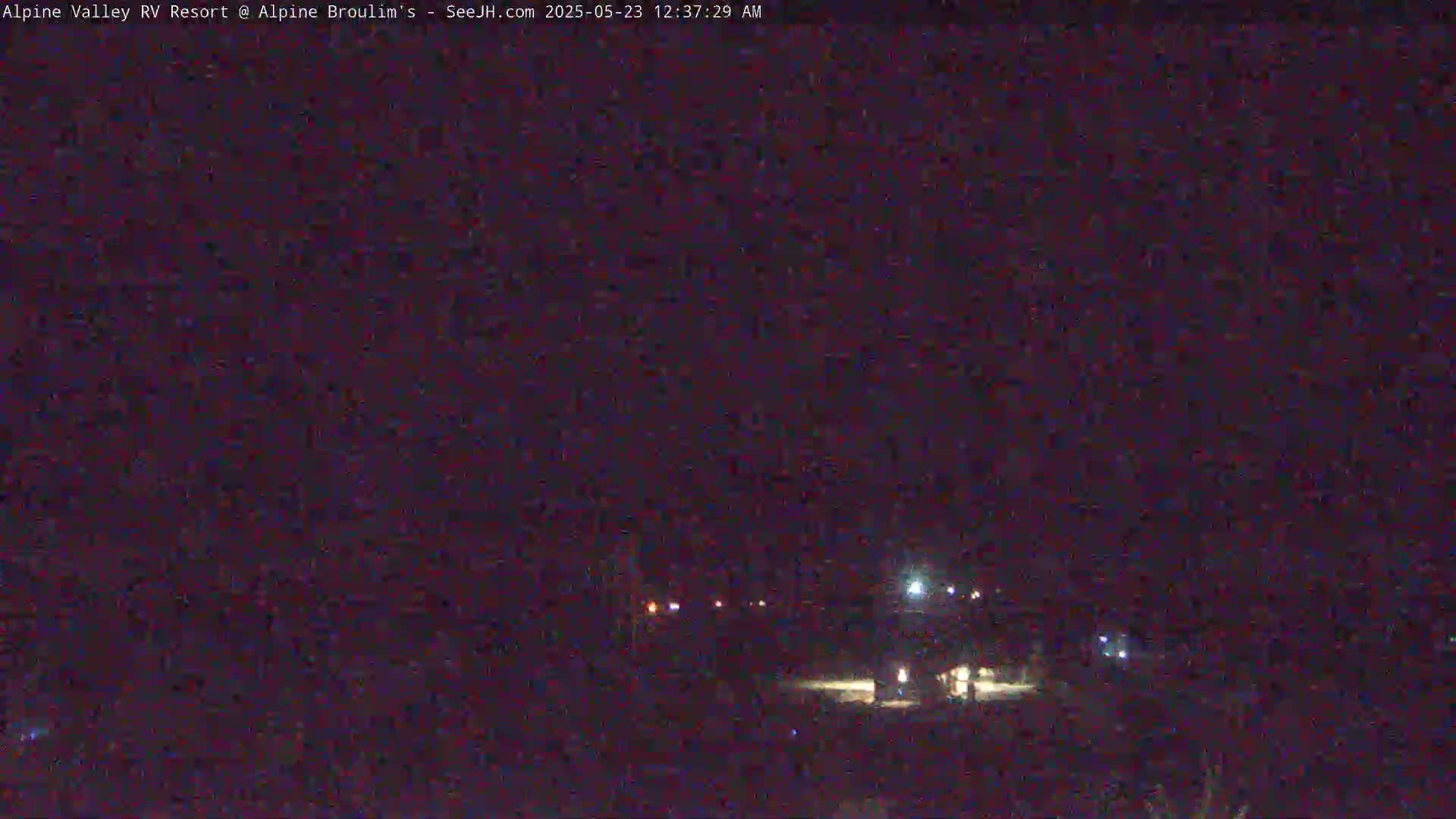 A dark nighttime scene shows a few scattered lights in the distance under a clear, dark sky.