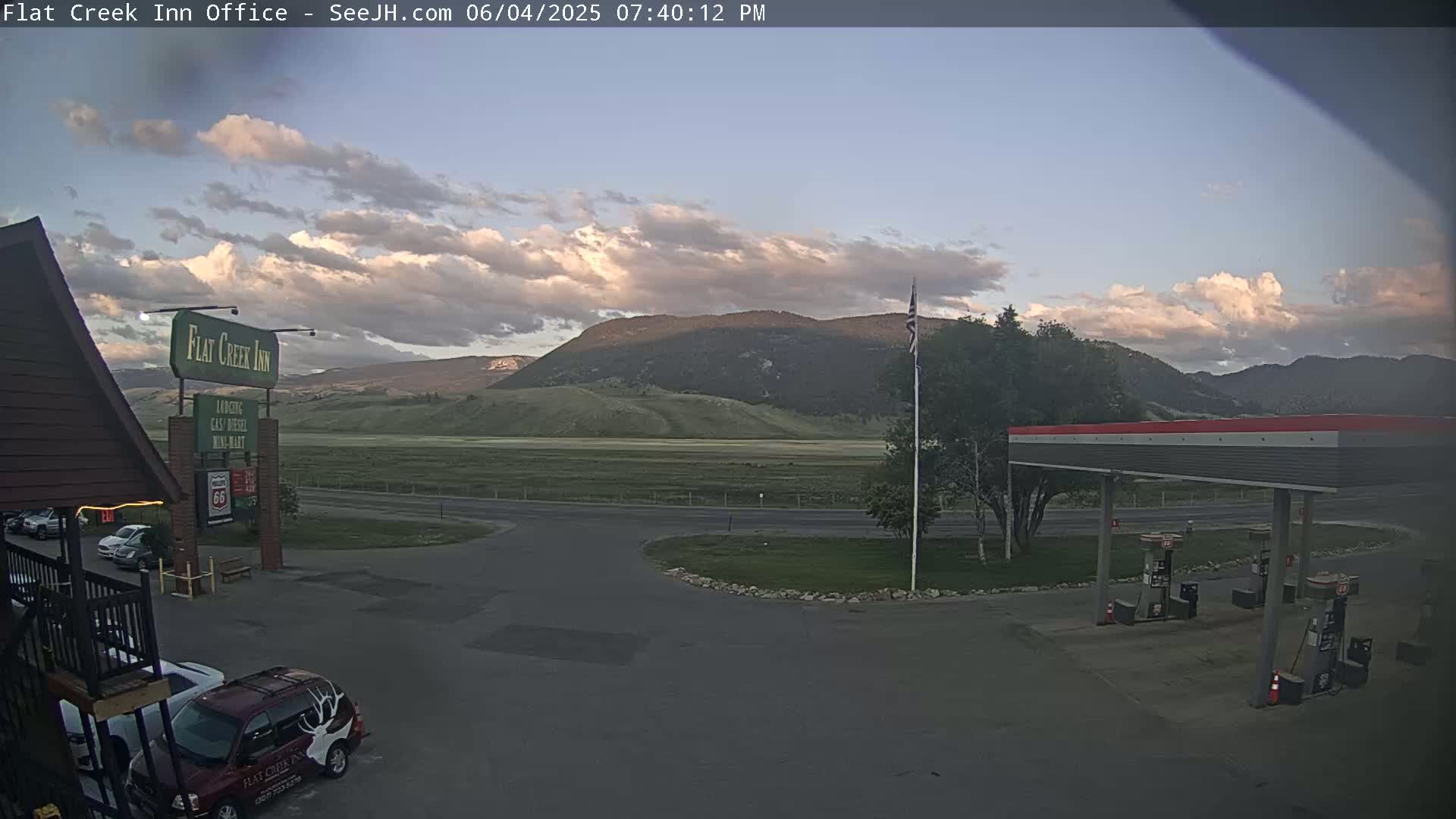A partly cloudy evening scene shows a gas station, a motel, and a mountain range in the background.