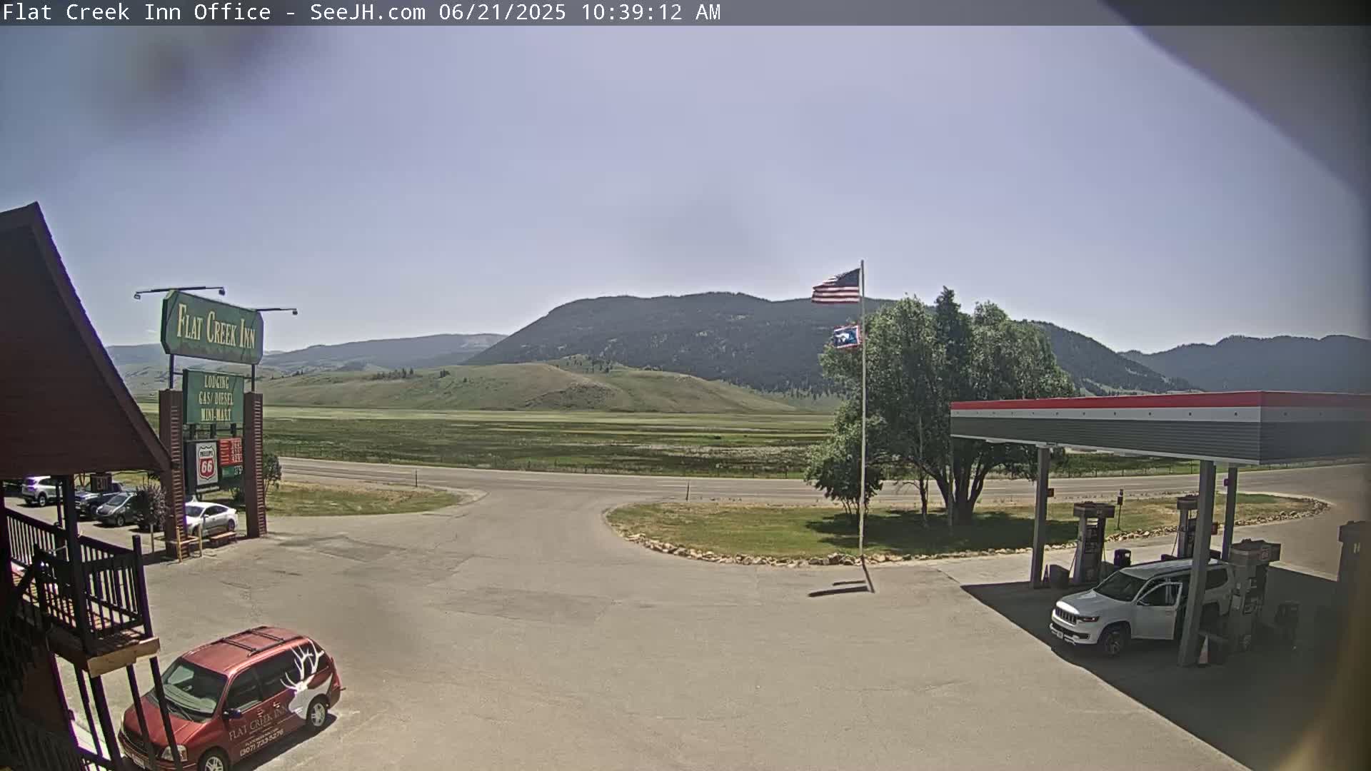 A sunny day reveals a gas station and motel in a valley, with mountains in the background.