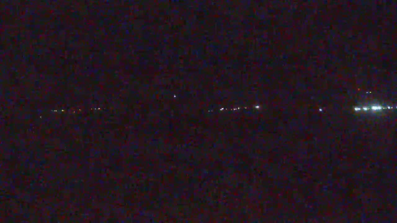 A nighttime view shows a distant line of lights on the horizon.