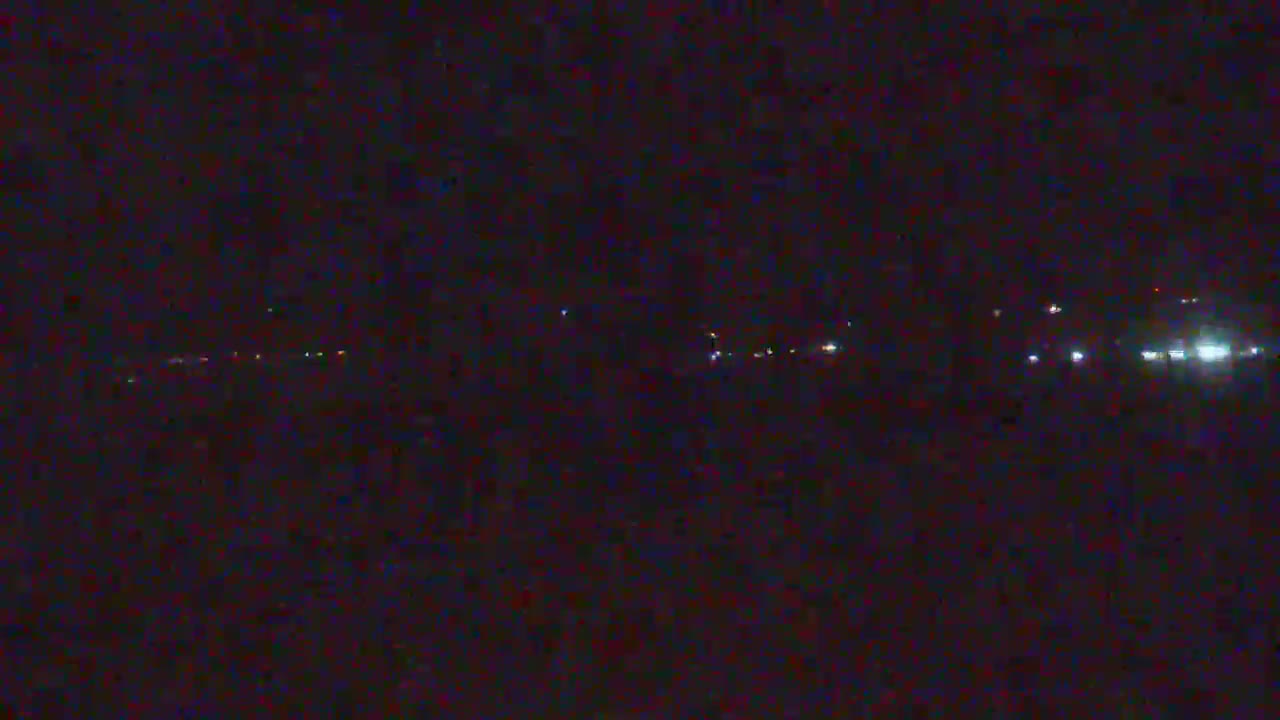 A dark, nighttime scene shows a distant line of faint lights.