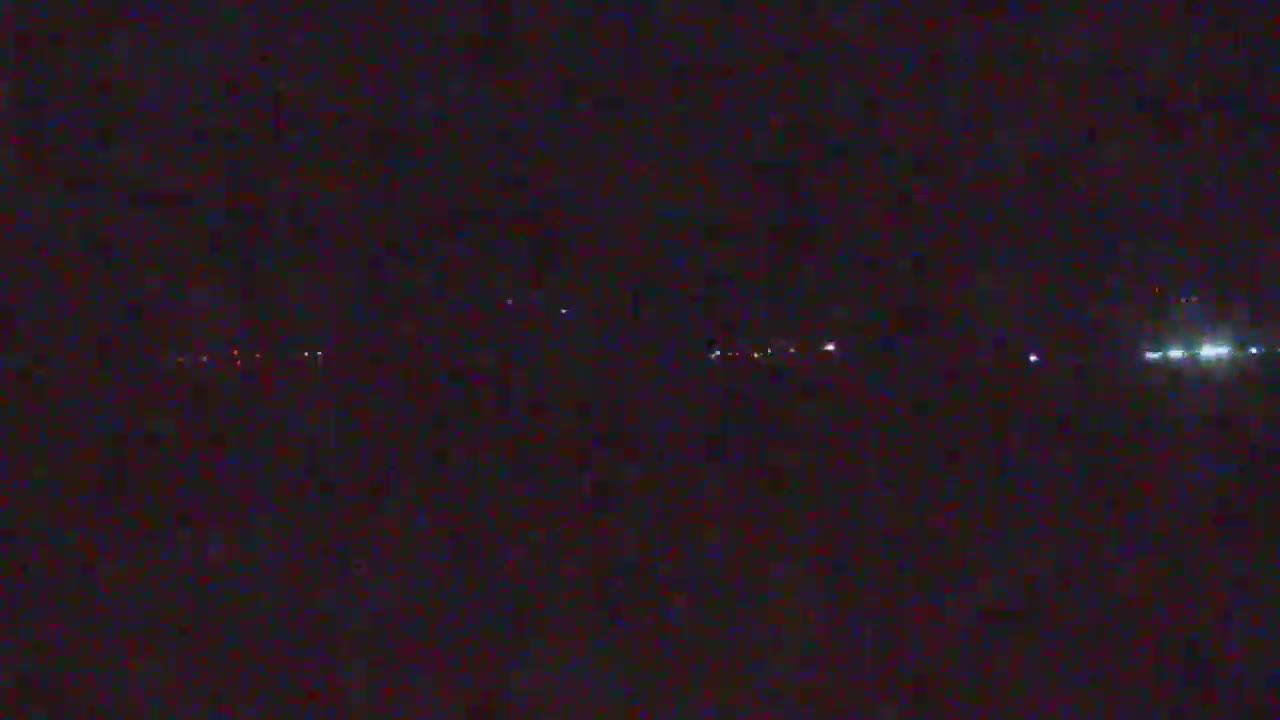 A nighttime long shot shows a line of faint lights in the distance on a dark horizon.