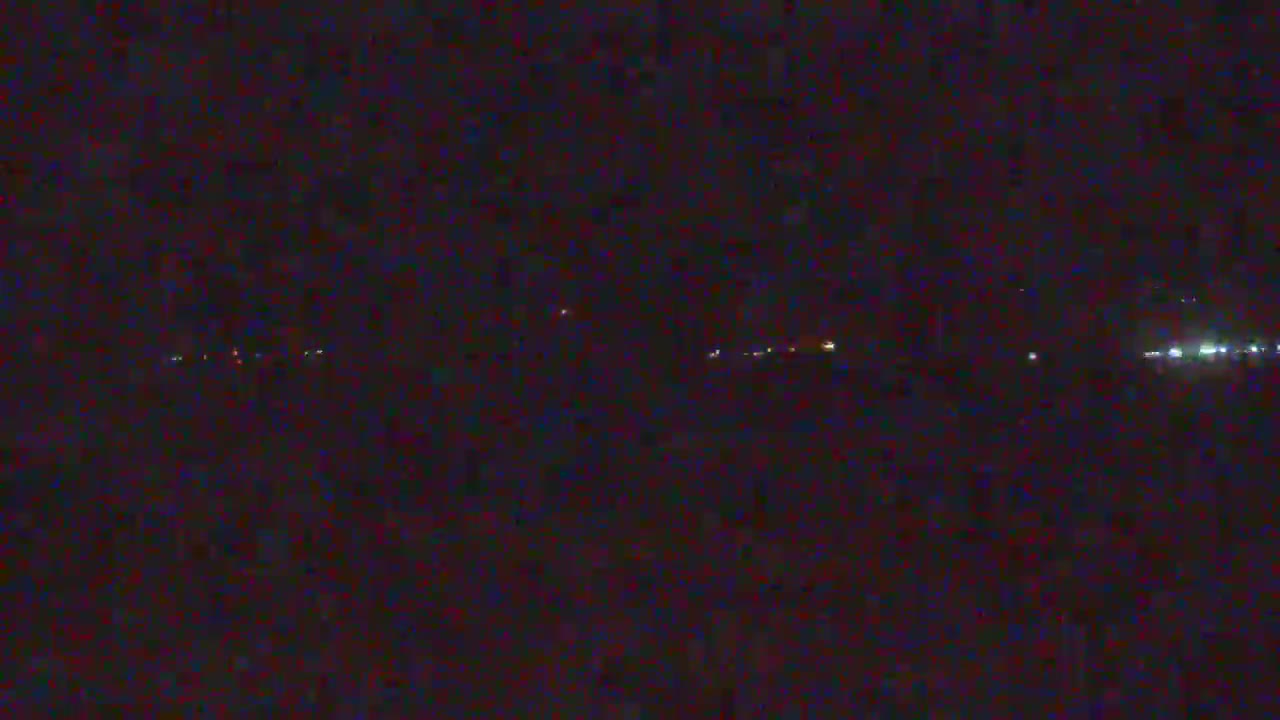 A nighttime long shot shows a dark landscape with a few faint lights visible in the distance.