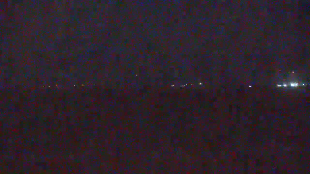 A nighttime, dark view shows a distant line of faint lights in the middle ground, likely from a town or city.