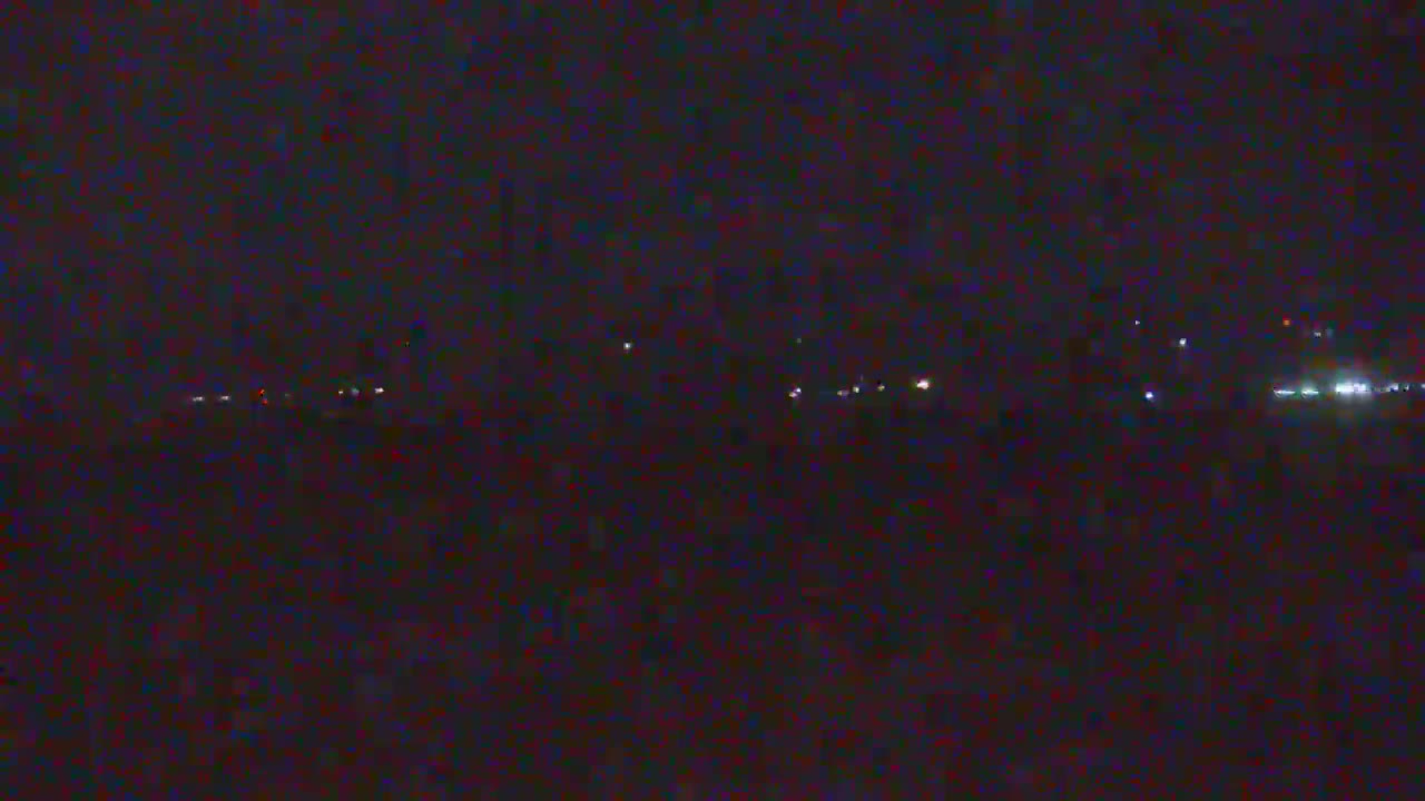 A dark, nighttime scene shows a distant line of faint lights on the horizon.
