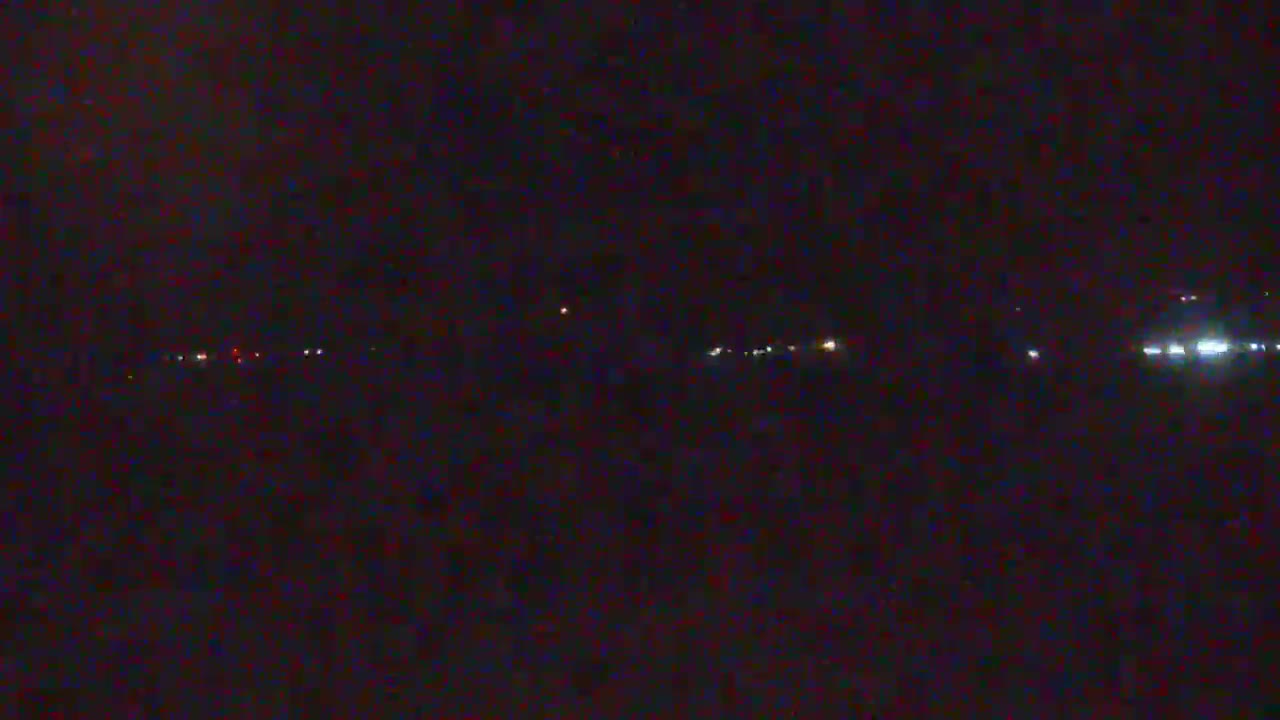 A dark, nighttime scene shows a distant line of faint lights possibly from vehicles or buildings.