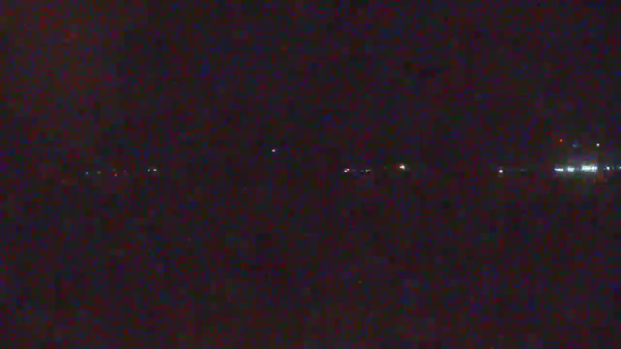 A dark nighttime scene shows a distant line of faint lights.