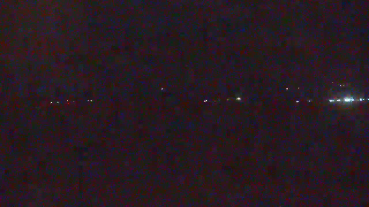 A nighttime, low-light view shows a dark expanse with a distant line of faint lights.