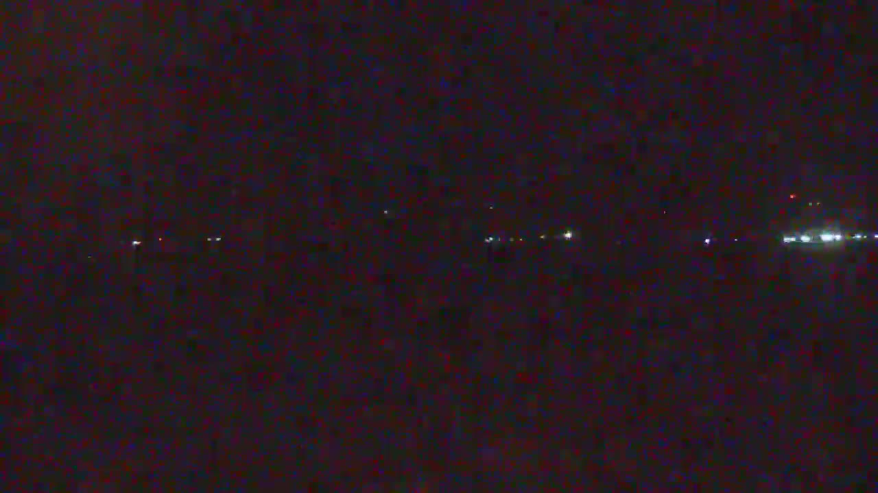 A dark, nighttime scene shows a distant line of faint lights on the horizon.