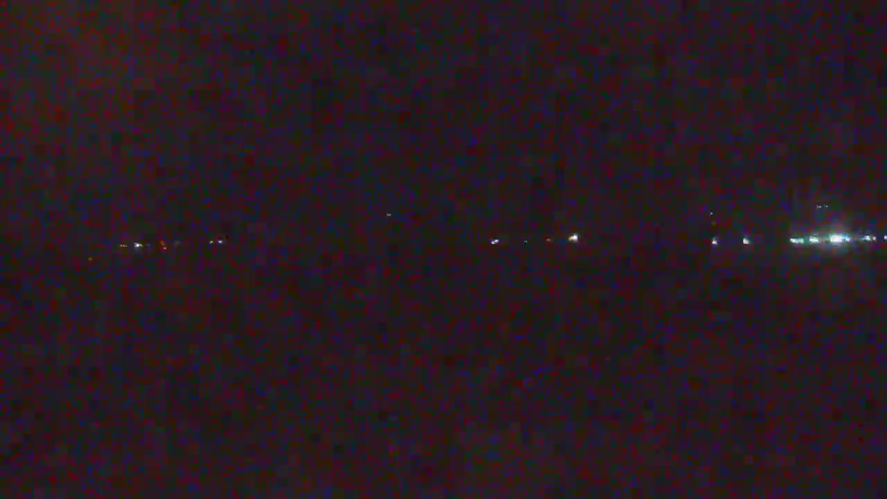 A dark, nighttime scene shows a distant line of faint lights on the horizon.