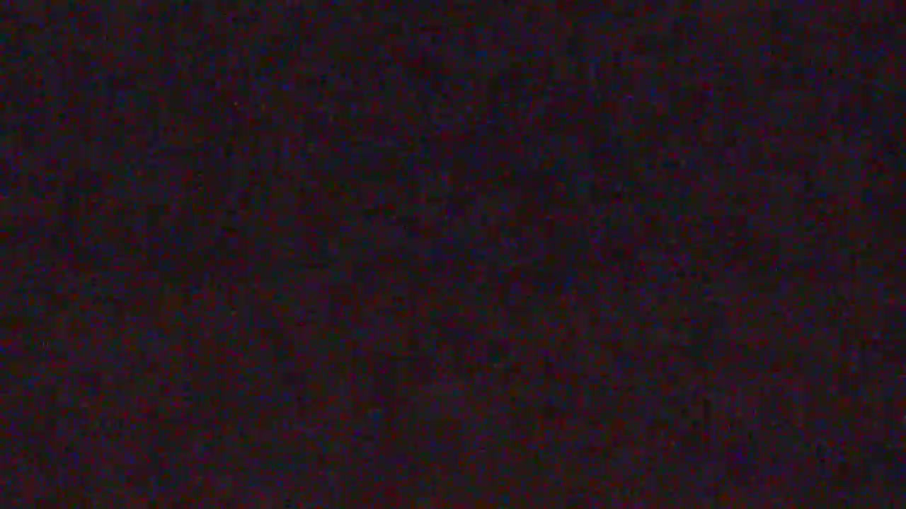 The image is a dark, almost black field with a significant amount of digital noise appearing as faint red, blue, and green speckles.