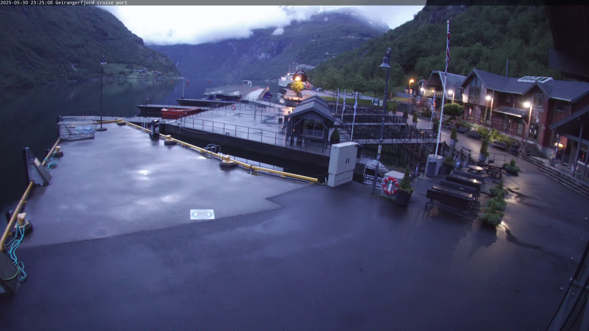 A wet cruise ship port at night, nestled between steep, dark green mountains and a calm body of water.