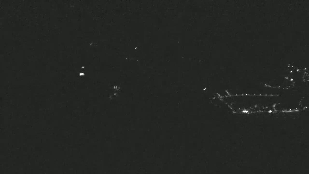 A nighttime, long-distance view shows a few scattered lights from what appears to be a small town or residential area in the distance.