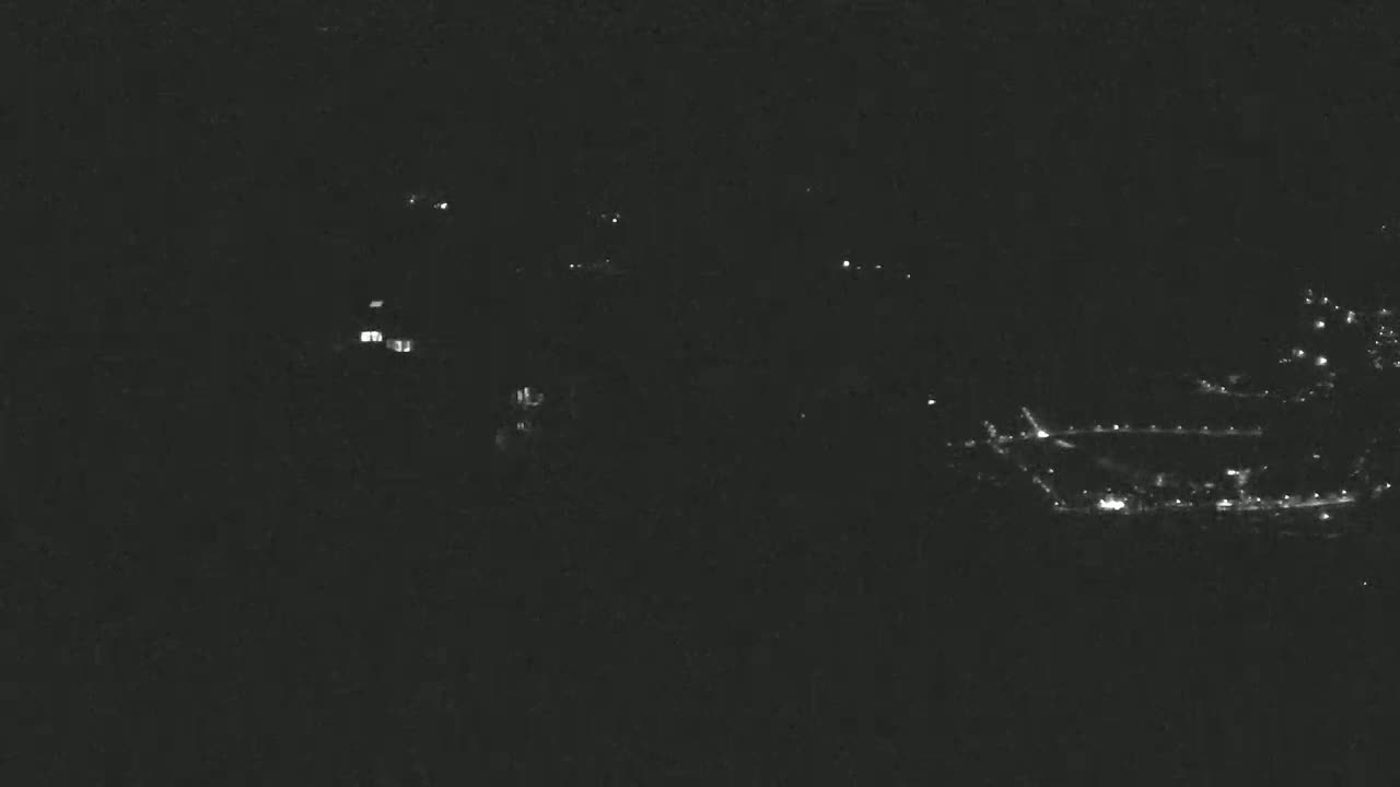 A nighttime, long-range view shows sparsely scattered lights in a dark, hilly landscape.