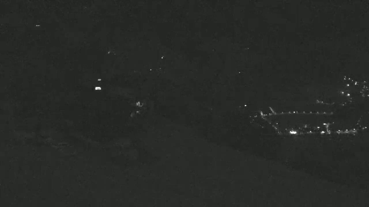 A nighttime long shot shows a dark landscape with sparsely scattered lights in the distance.