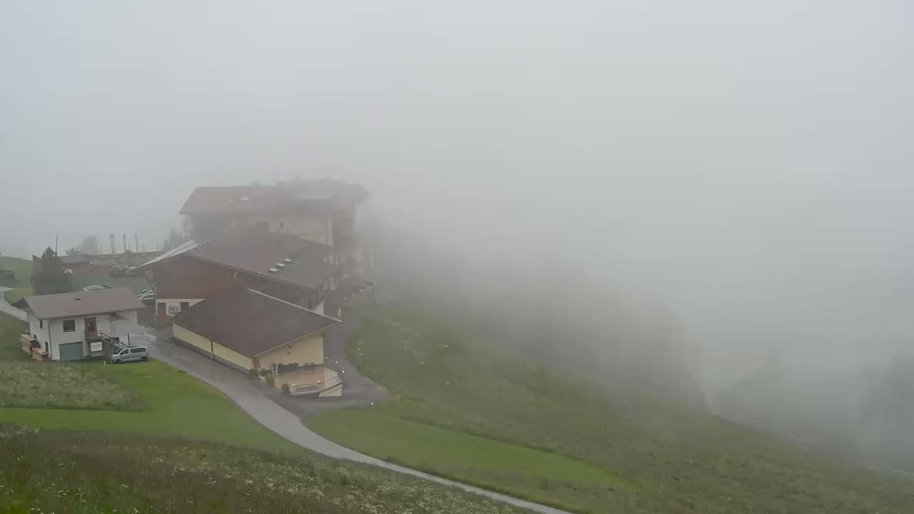 Several buildings are situated on a grassy hillside shrouded in thick fog.