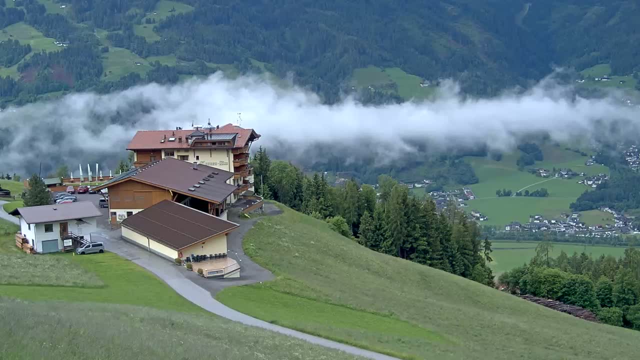A hillside hotel complex overlooks a valley shrouded in fog, with a village visible in the distance.