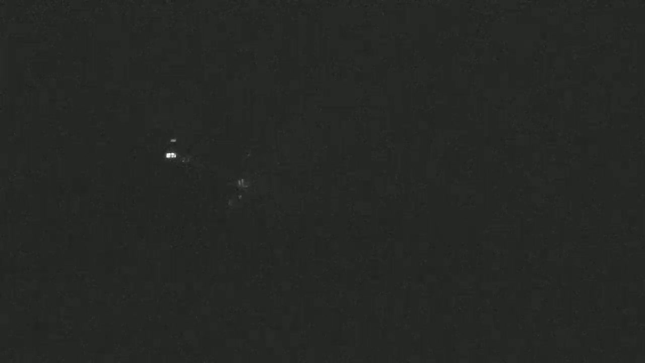 A nighttime, dark image shows a few faint, distant lights.