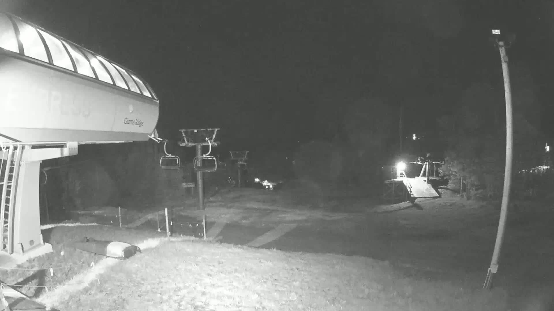 A chairlift loading station at night, with a chairlift extending into the darkness.