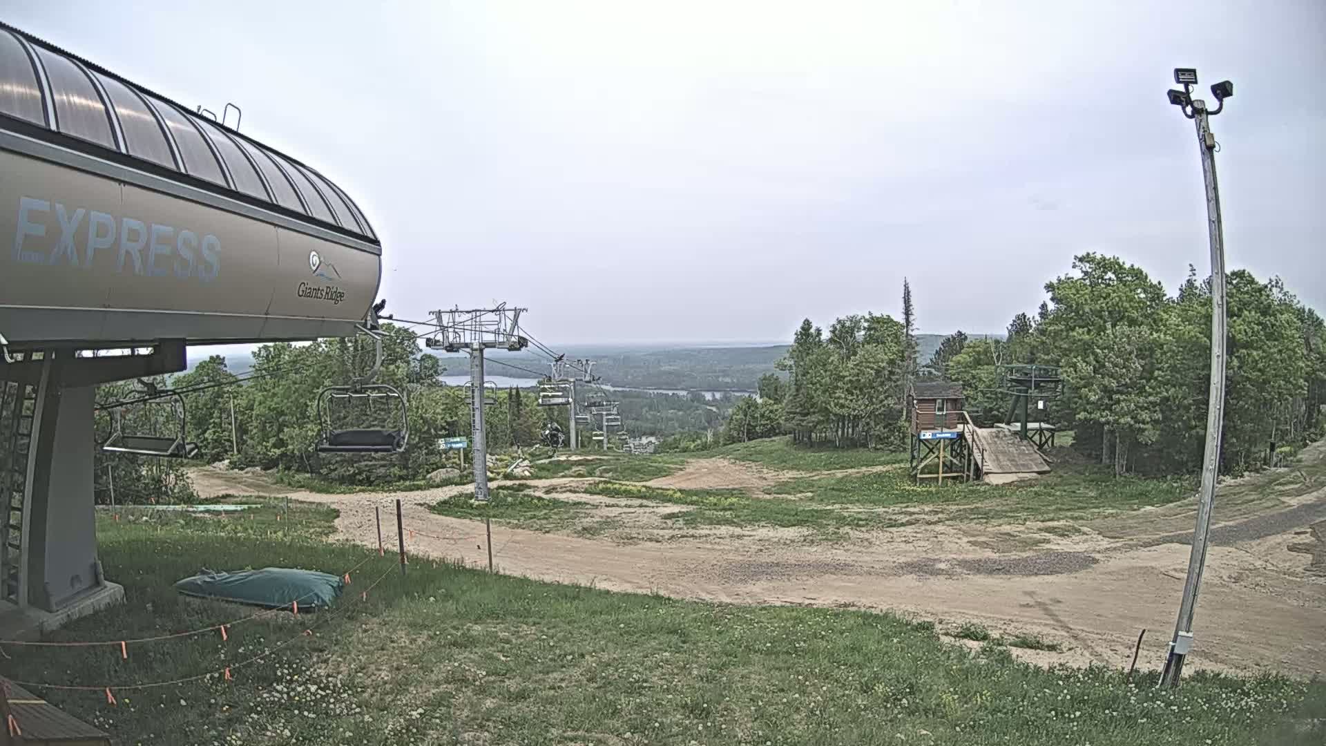 A chairlift at a ski resort overlooks a hilly landscape under an overcast sky.