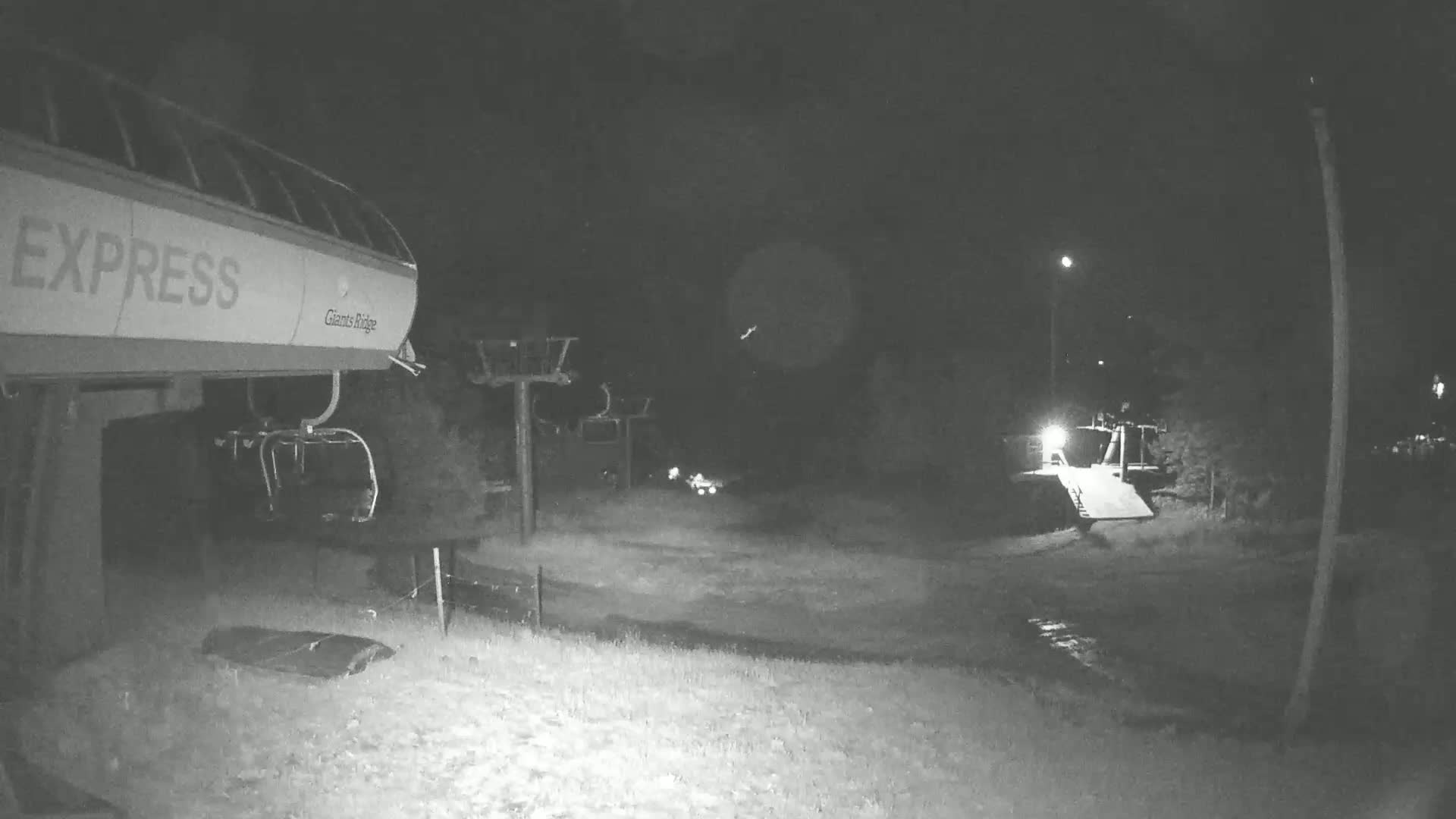 A nighttime, low-light view of a chairlift and ski lift infrastructure at a ski resort.