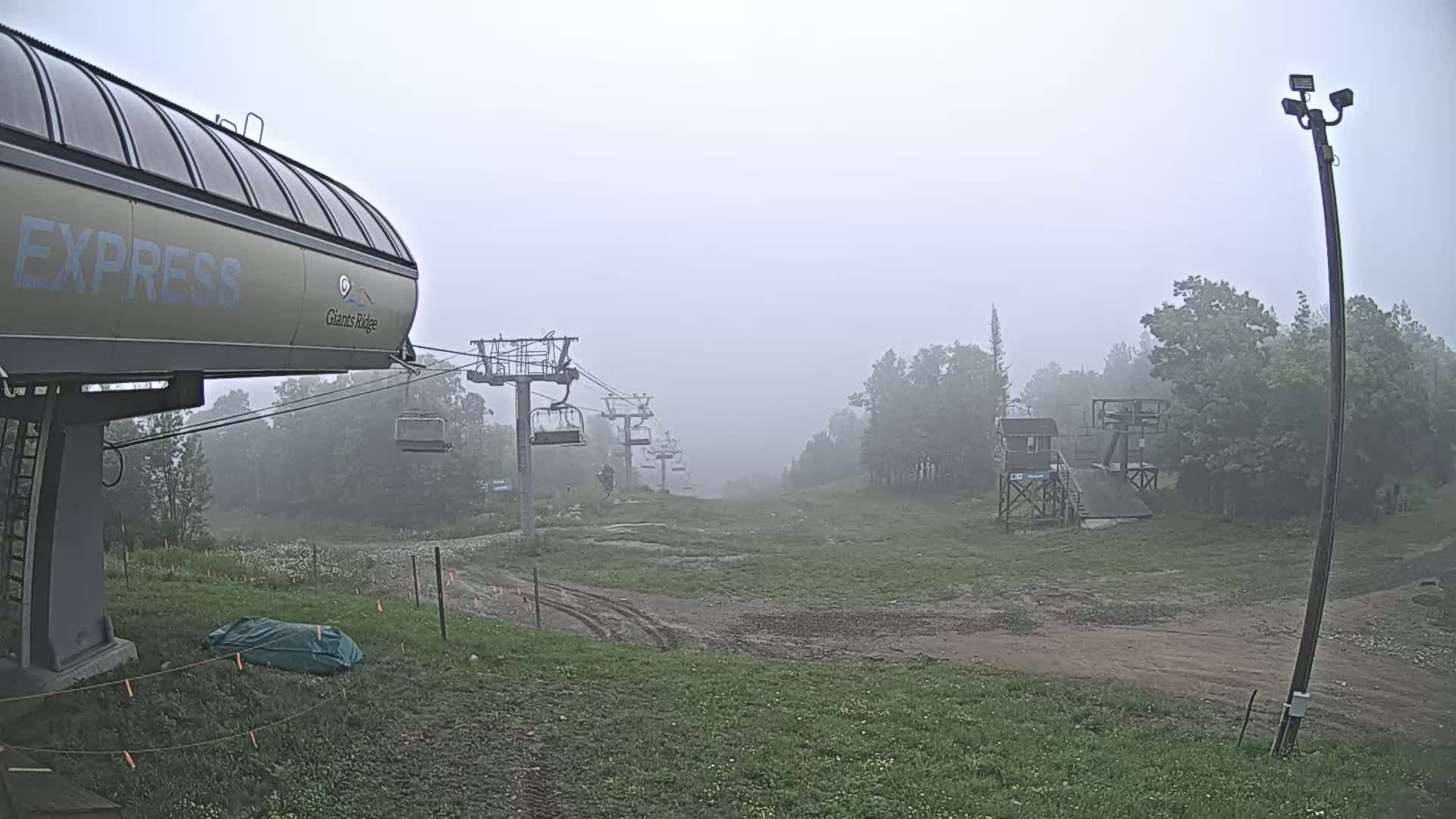 A nighttime, snowy scene shows part of a ski lift and a snow-covered ground.