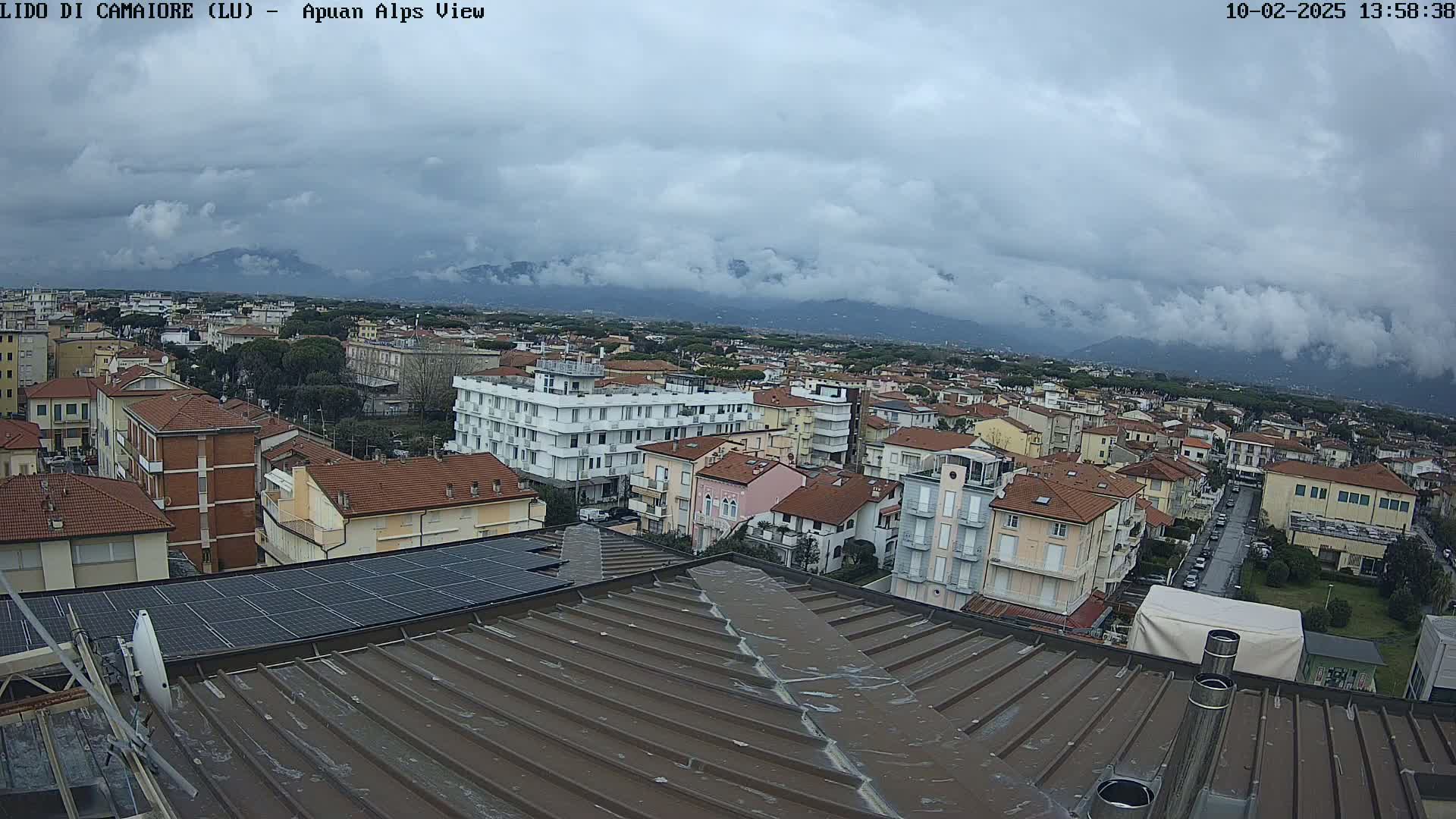 A cloudy day overlooks a town of low-rise buildings and a distant mountain range.