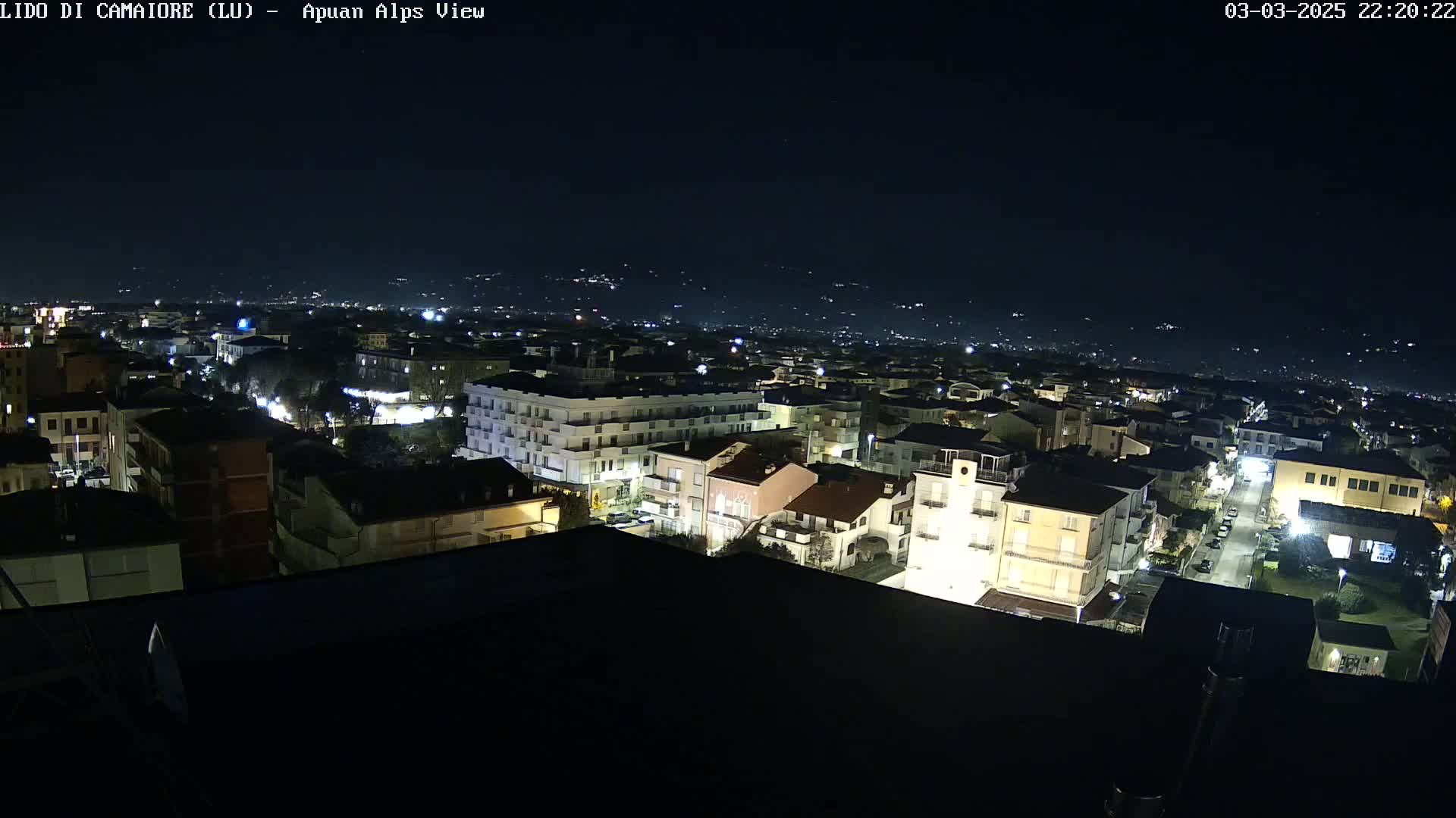 A nighttime, aerial view of a town with illuminated buildings and streets, under a clear, dark sky.