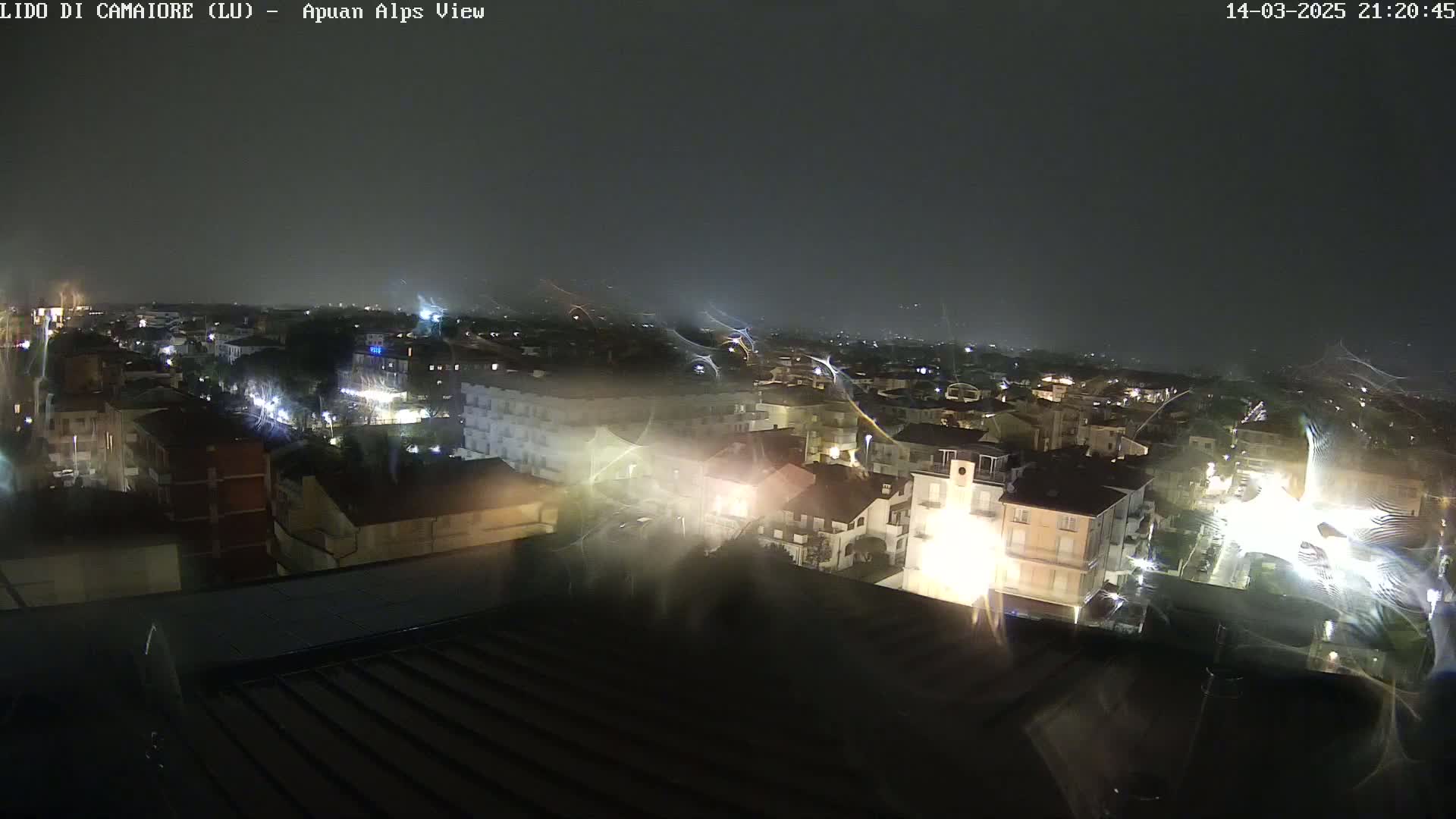 A nighttime view of a town illuminated by streetlights under a dark, possibly rainy sky.