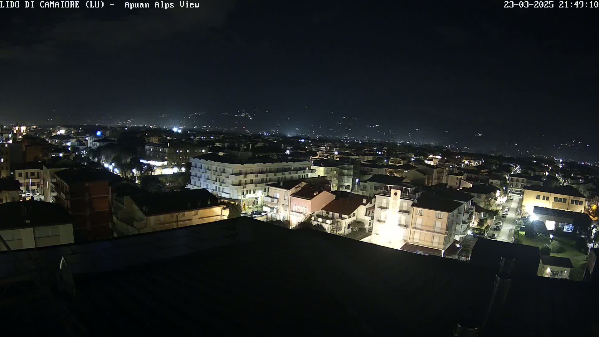 A nighttime aerial view of a town, showing numerous buildings lit up under a clear, dark sky.