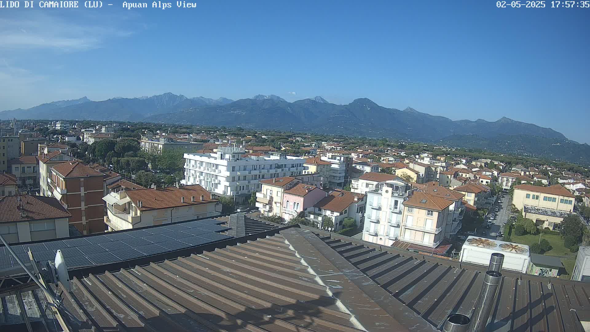 A rooftop view of a town on a clear day, with mountains in the background.