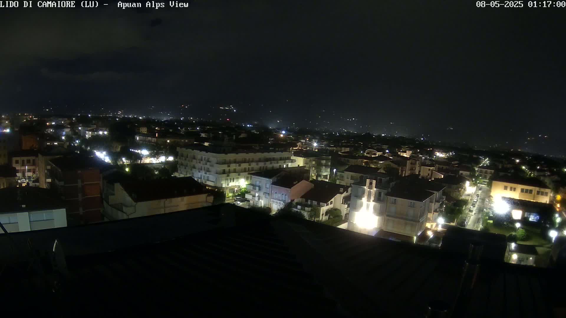 A nighttime, aerial view of a town with its lights on, under a dark sky.