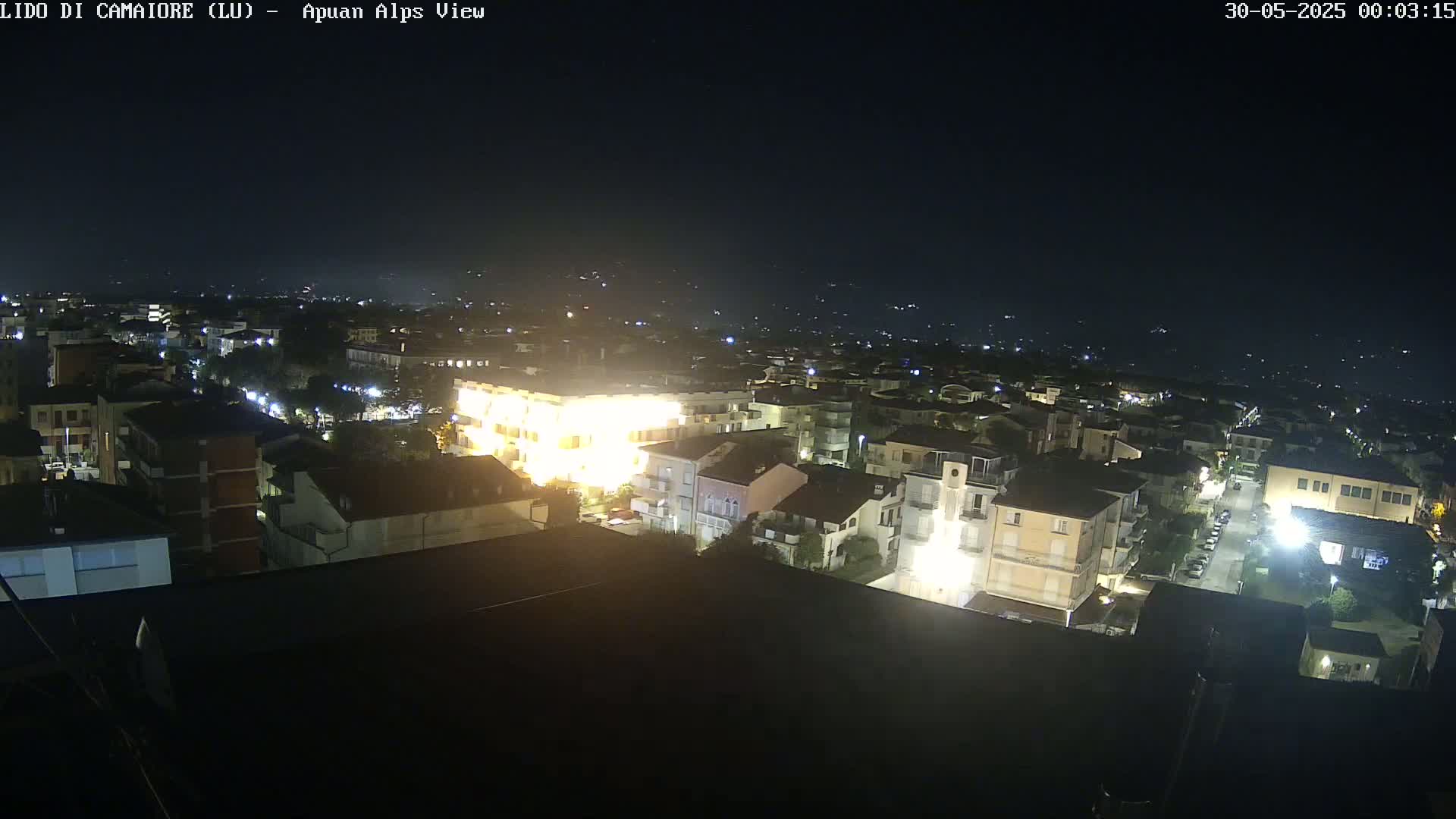 A nighttime, high-angle view shows a town illuminated by streetlights and building lights under a clear, dark sky.