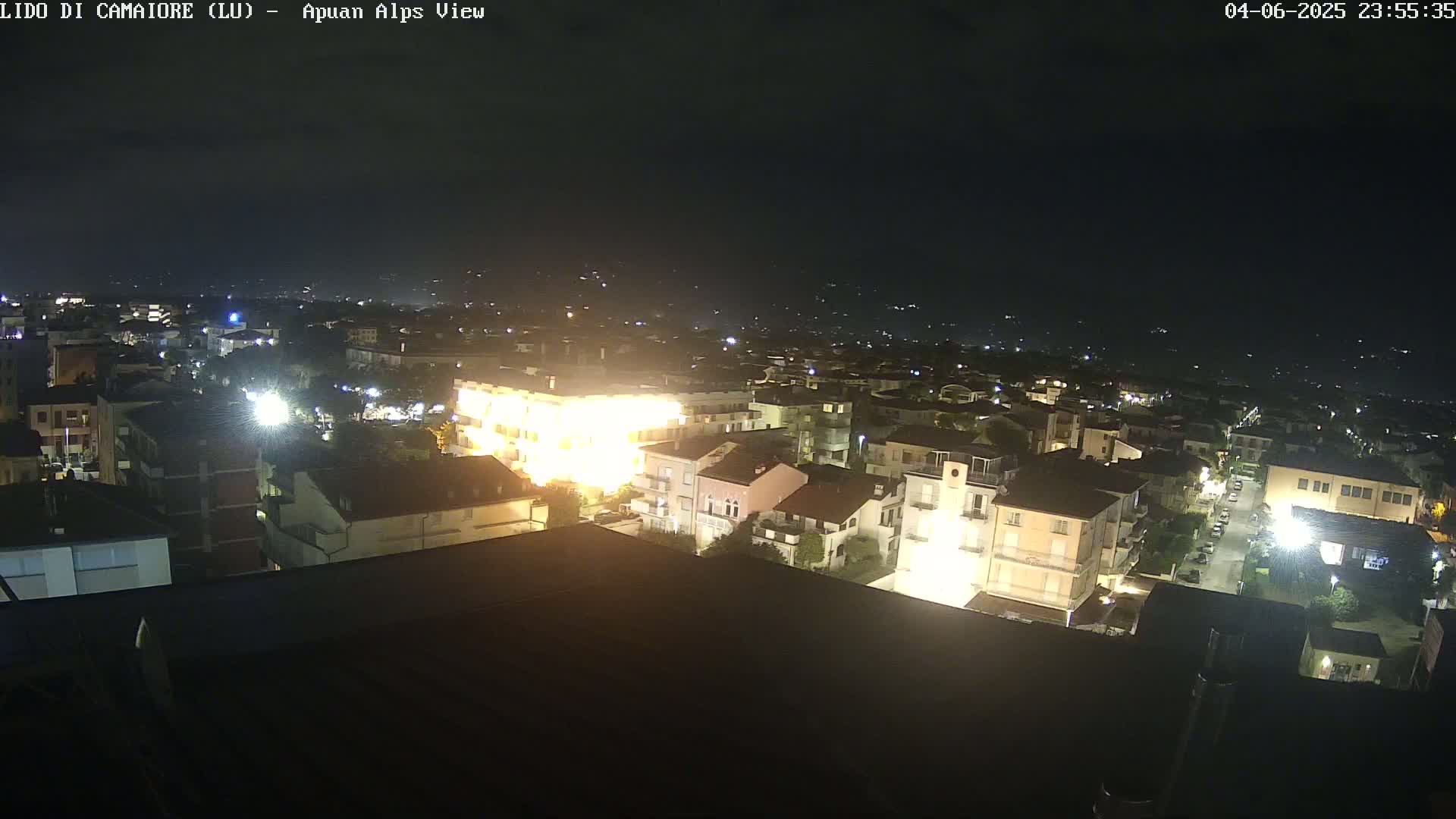 A nighttime, aerial view of a town with brightly lit buildings, under a clear, dark sky.