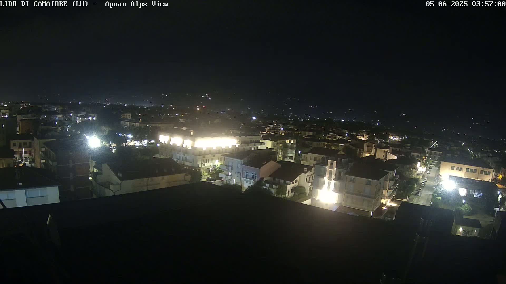 A nighttime, high-angle view of a town with brightly lit buildings and streets.