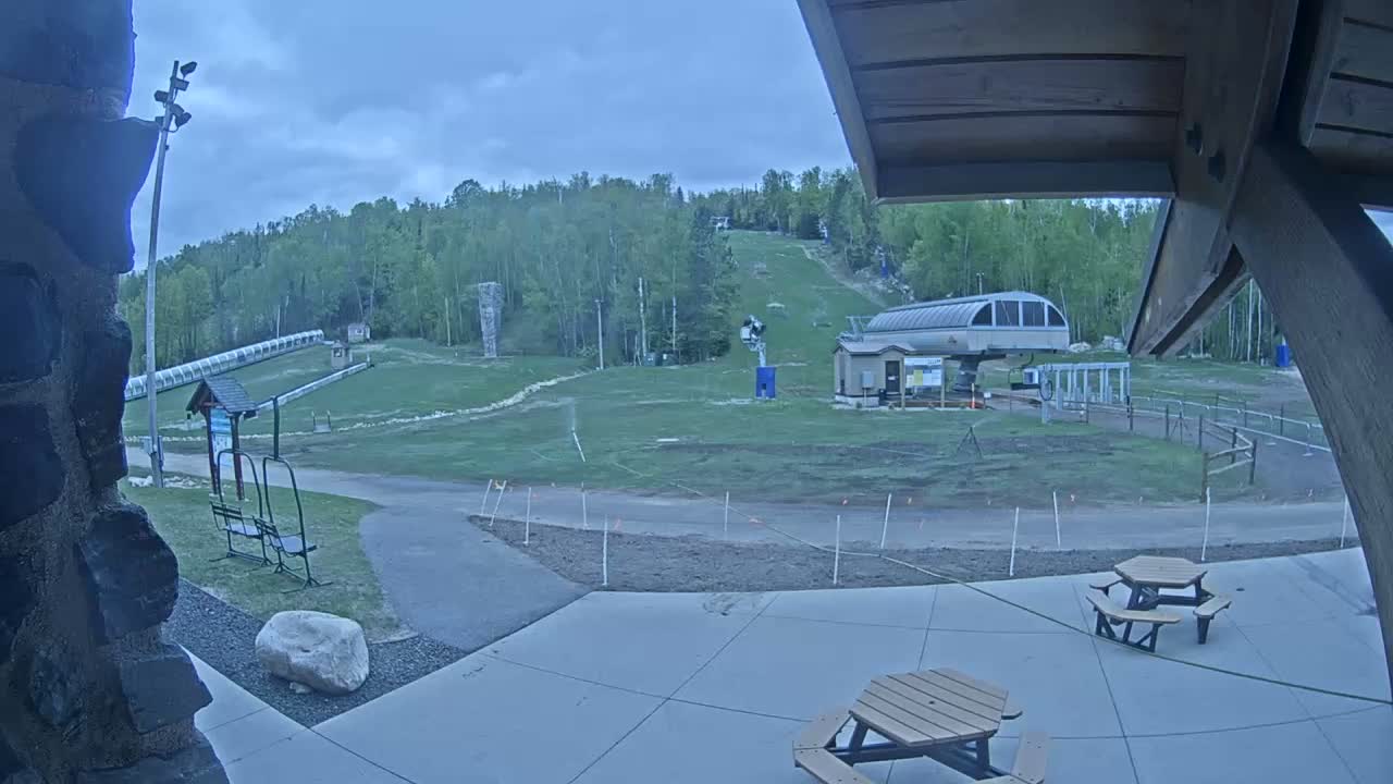 A ski hill with a chairlift and grassy areas is visible from a patio under an overcast sky.