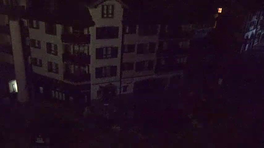 A multi-story building is visible at night, dimly lit with a few lights on inside.